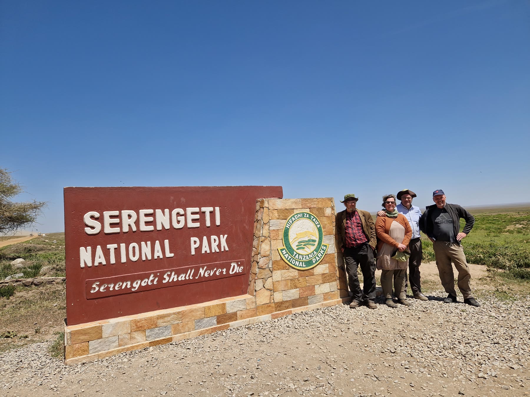 Ferðahópur við skilti Serengeti-þjóðgarðsins